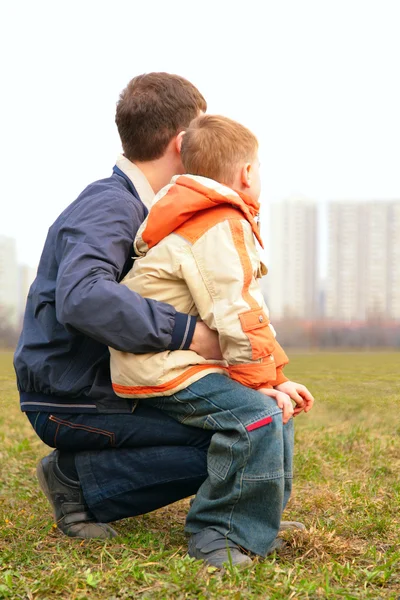 Son on lap of father outdoor in city from back — Stock Photo, Image