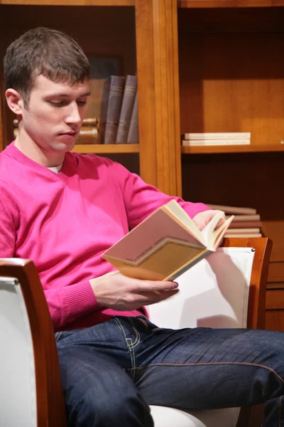 Jeune homme lit livre dans la chambre — Photo