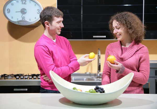 Junges Paar in der Küche mit Früchten in der Hand — Stockfoto