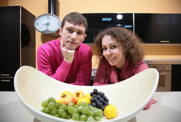 Νεαρό ζευγάρι στην κουζίνα και το αγγείο με φρούτα — Φωτογραφία Αρχείου