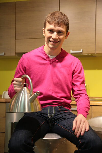 Young man in kitchen with steel kettle