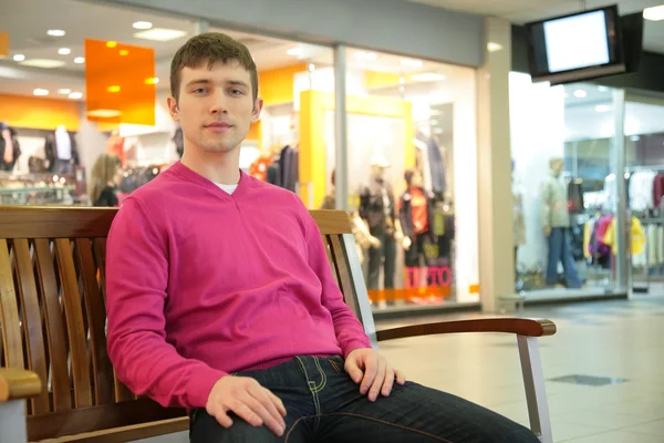 Young man sits on bench in mall — Stock Photo, Image