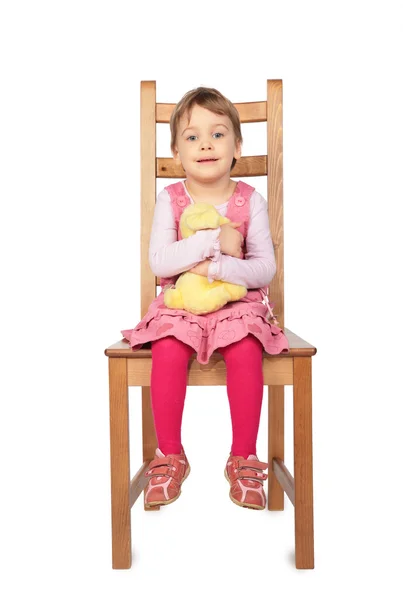 Meisje met speelgoed zitten op kruk — Stockfoto