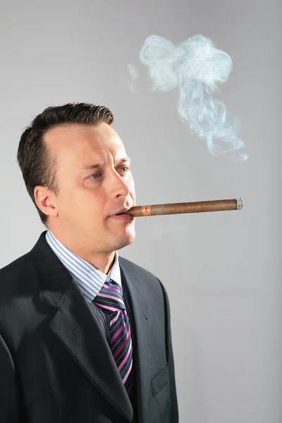 Businessman smokes a cigar — Stock Photo, Image