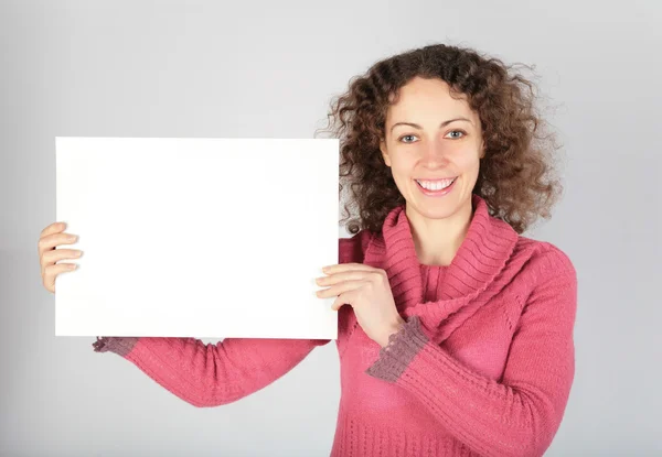 Молодая женщина держит белый лист бумаги — стоковое фото