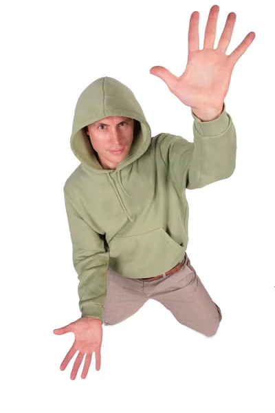 Man in jacket with hood is kneeling and has rised hand — Stock Photo, Image