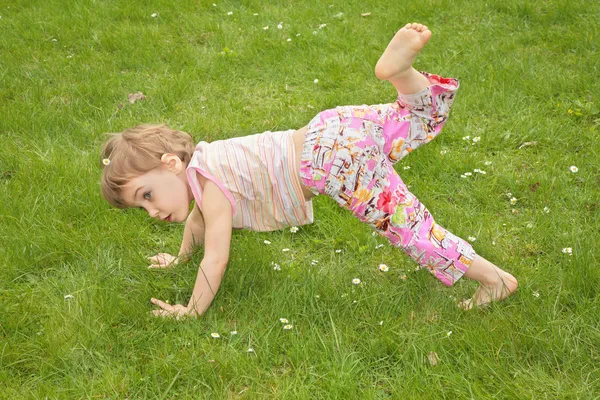 Маленькая девочка делает гимнастические упражнения на траве — стоковое фото