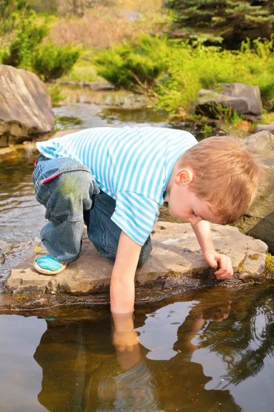 Boy has lowered hand in stream — Stock Photo, Image