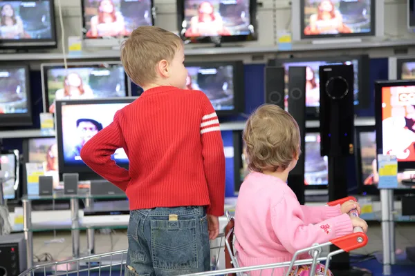 Děti v kočáře za nákupy pohled na TV v obchodě — Stock fotografie