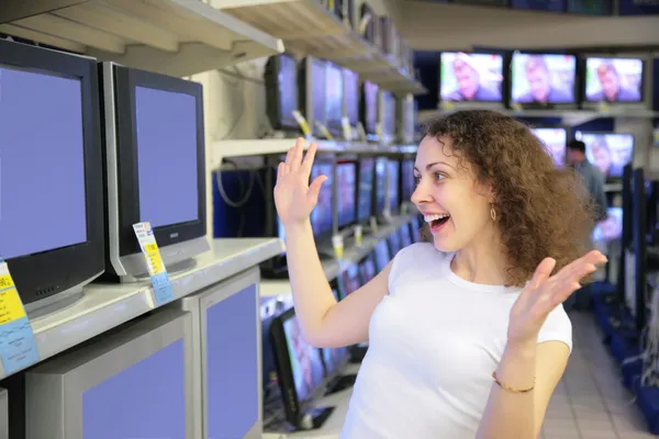 Jonge vrouw in verrukking kijkt TV's in winkel — Stockfoto