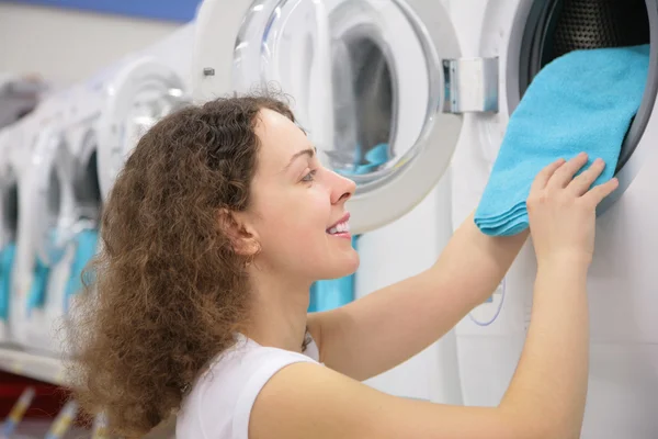Молодая женщина кладет белье в стиральную машину в магазине — стоковое фото