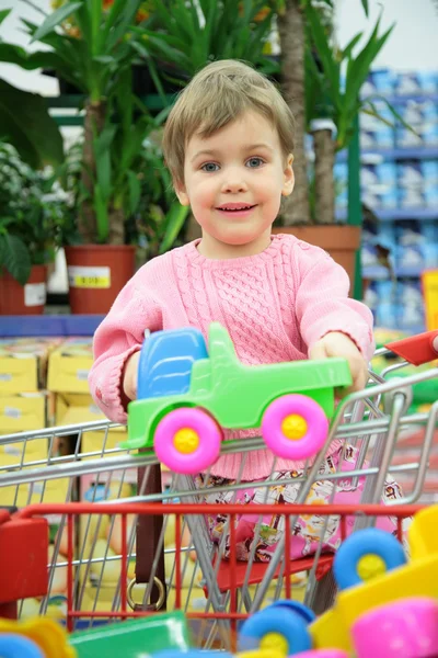 Child in shoppingcart with toy car — Stock Photo, Image