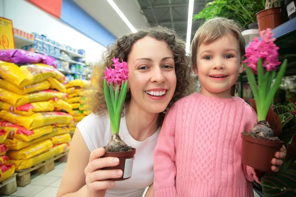 Madre e hija sostienen macetas con flores en la tienda —  Fotos de Stock