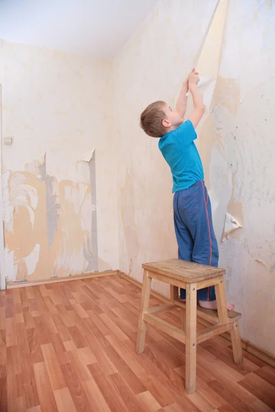 Jongen breekt wallpapers van muur — Stockfoto
