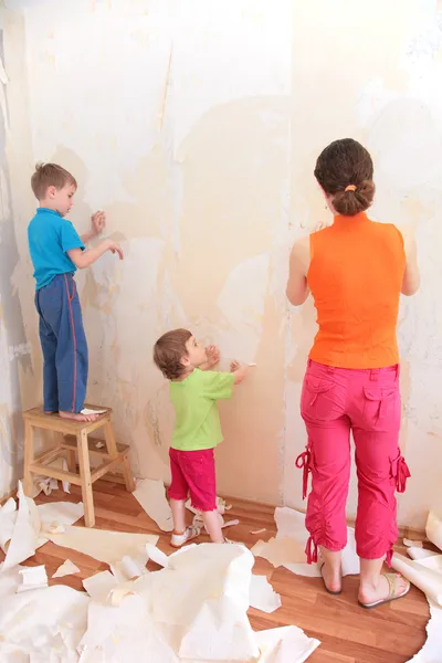 Mãe com crianças remover papéis de parede velhos — Fotografia de Stock