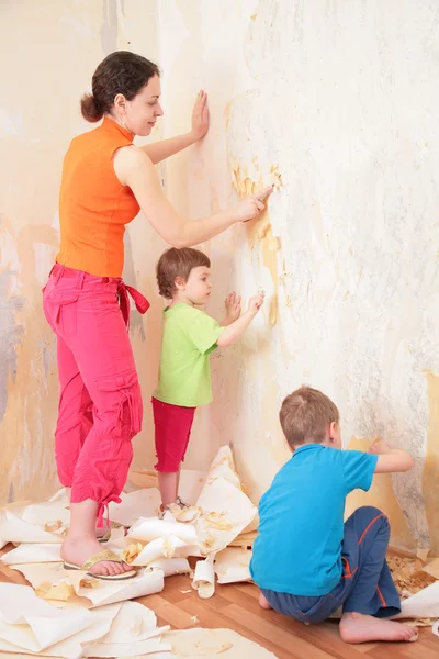 Crianças ajudar a mãe remover da parede velhos papéis de parede — Fotografia de Stock