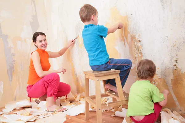 Gyermekek segít anya a régi tapéta eltávolítása — Stock Fotó