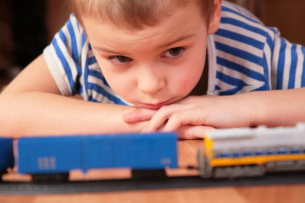 Rapaz olha para a ferrovia de brinquedo — Fotografia de Stock