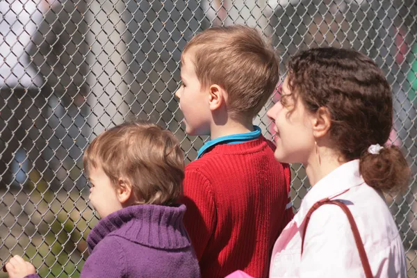 Mère et enfants regardent à travers le treillis — Photo