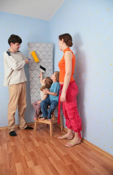 Τα παιδιά βοηθούν τους γονείς να κολλήστε ταπετσαρίες τοίχου — Φωτογραφία Αρχείου