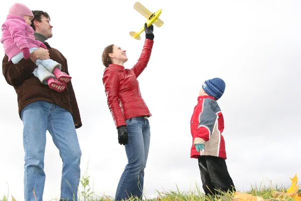 Rodina stojí na louce na podzim s hračkou letadla — Stock fotografie