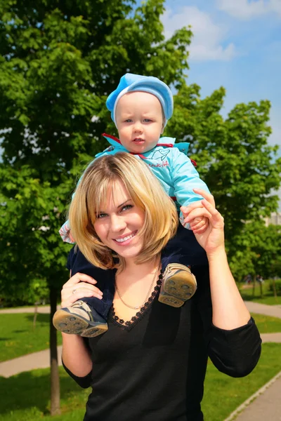 Мать держит ребенка на плечах на открытом воздухе — стоковое фото
