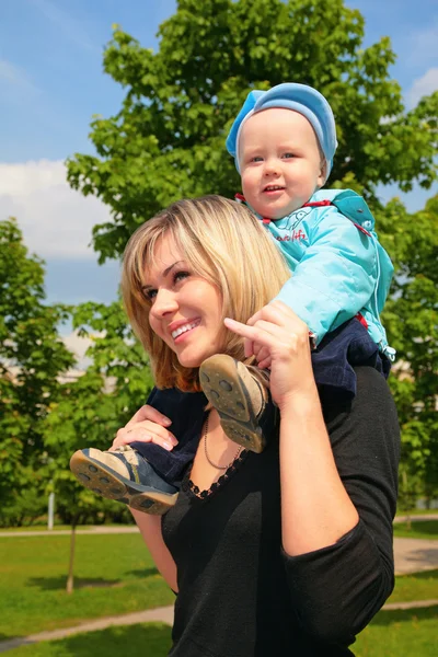Мати з дитиною на плечах на відкритому повітрі — стокове фото