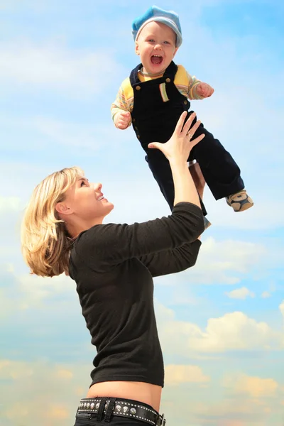 Mãe levanta criança a mãos ao ar livre — Fotografia de Stock