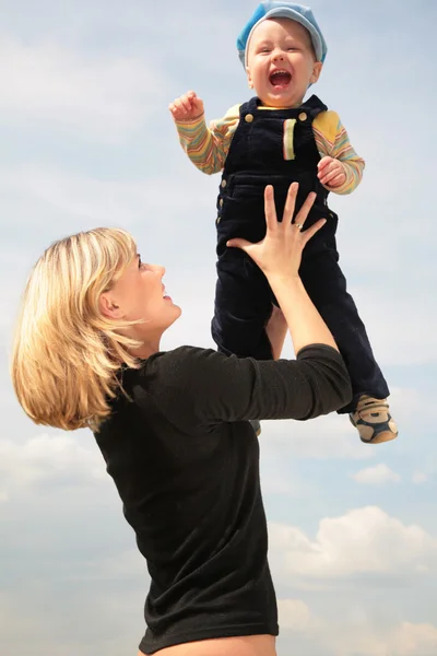 Mãe levanta criança a mãos — Fotografia de Stock