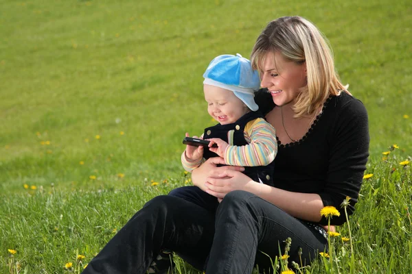 Matka s dítětem sedět na trávě — Stock fotografie