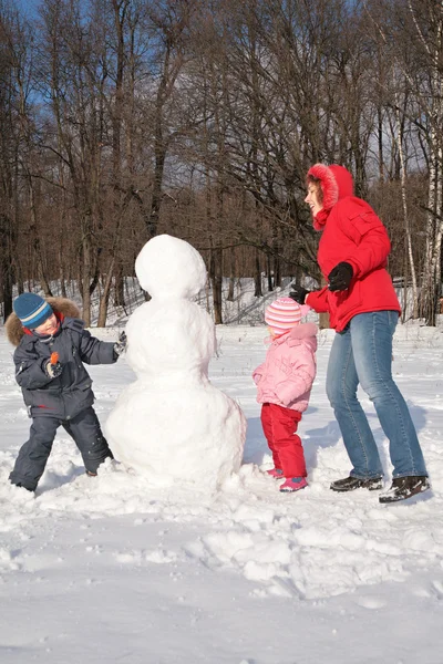 Moeder en kinderen maken sneeuwpop — Stockfoto
