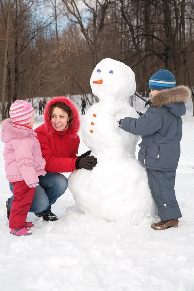 Мать и дети делают снеговика — стоковое фото