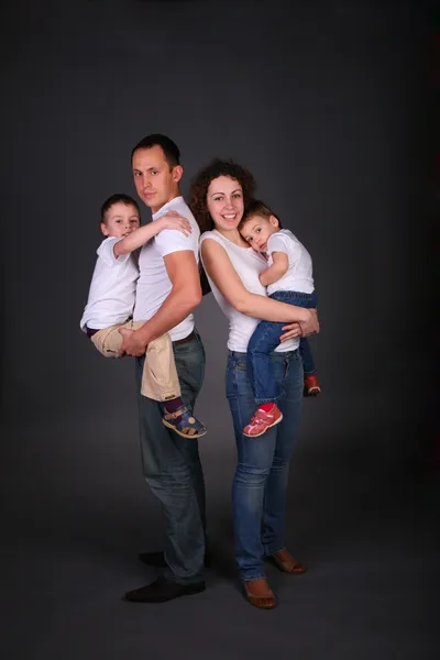 Родители держат детей на руках на темном фоне — стоковое фото