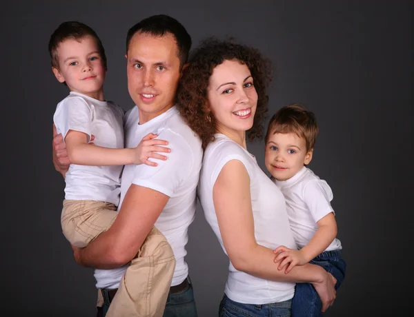 Родители с детьми на руках на темном фоне — стоковое фото