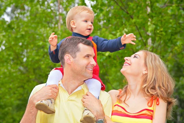 Family in park with child on shoulders — Stock Photo, Image