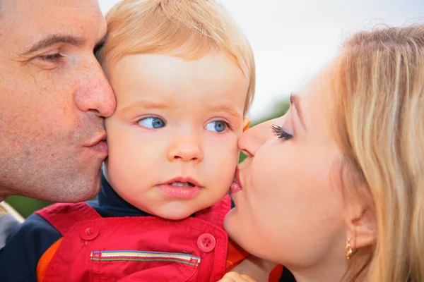 Родители целуют ребенка на улице — стоковое фото