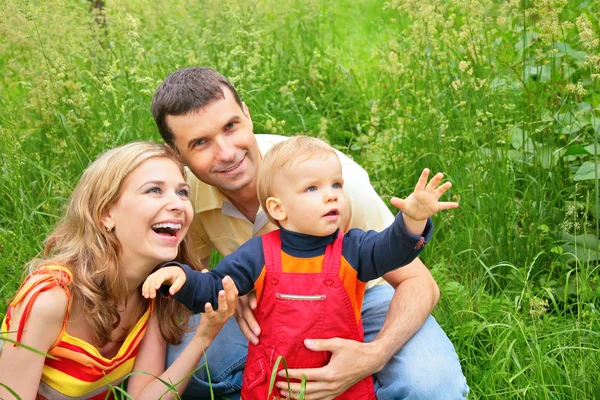 Родители с ребенком сидят в траве и смотрят вверх — стоковое фото