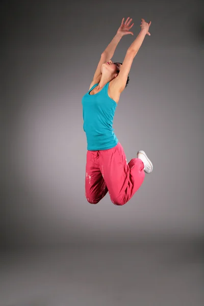 Танцююча жінка в спортивному одязі в стрибку з піднятими руками — стокове фото