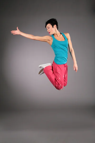 Mujer bailando en ropa deportiva en salto con la mano estirada — Foto de Stock