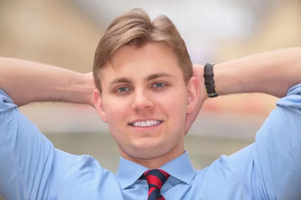 Young businessman holds hands behind head — Stock Photo, Image