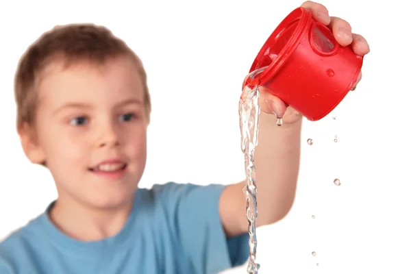 Chłopiec rozlewa się wody z czerwony kubek z tworzyw sztucznych — Zdjęcie stockowe