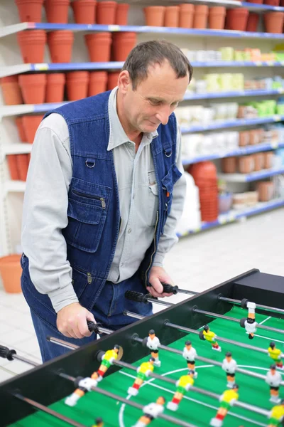 Homem joga futebol de mesa na loja — Fotografia de Stock