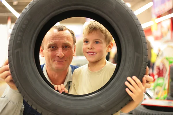 Rapaz e homem olham para o pneu do veículo na loja — Fotografia de Stock