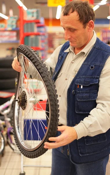 Homem detém roda de bicicleta curva na loja — Fotografia de Stock