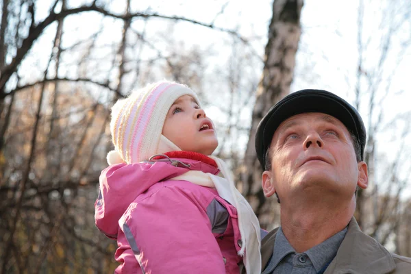 Grandfather with granddaughter on hands outdoor look upward — Stock Photo, Image