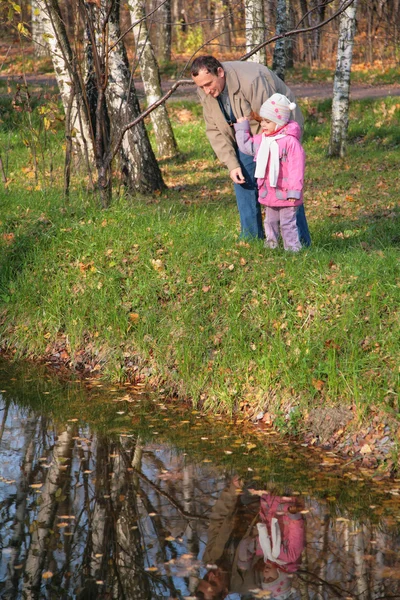 Grandfather with granddaughter in wood in autumn look in water — Stock Photo, Image