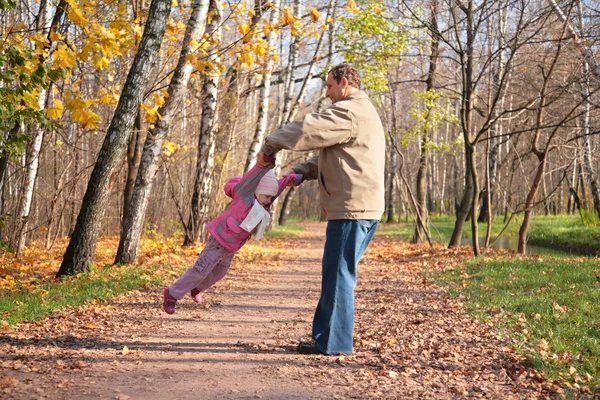 Großvater lässt Enkelin im Herbst im Wald rotieren — Stockfoto