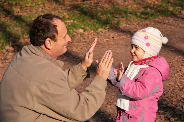 Grandfather plays with granddaughter in wood in autumn — Stock Photo, Image