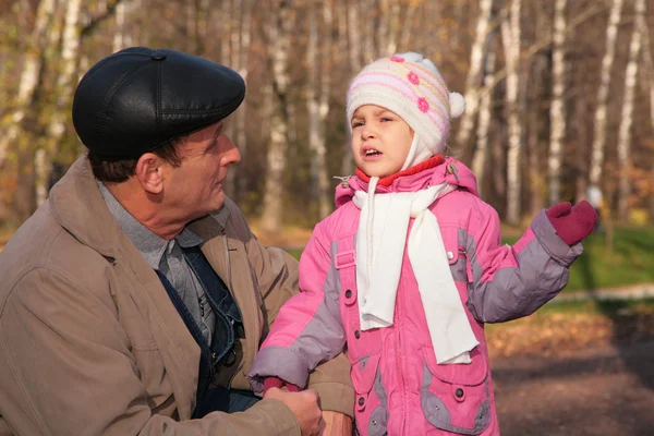 Grootvader gesprekken met kleindochter in hout in de herfst — Stockfoto