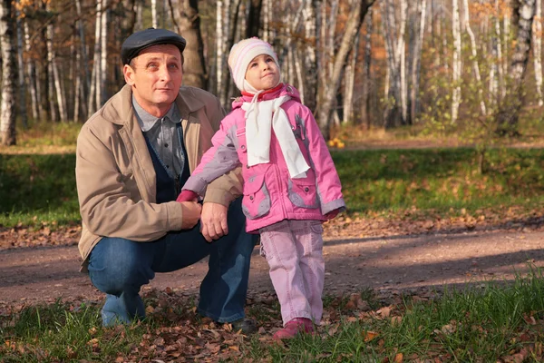 Grandfather with granddaughter in park in autumn look upward — Stock Photo, Image